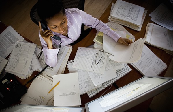 Businesswoman on telephone surrounded by paperwork,
