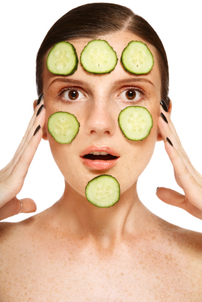 Young freckled woman with cucumber mask on her face and funnu expression, on white background